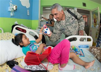 Senior Master Sgt. Arellano gives a Chilean girl a gift ans a smile during a visit to the Children's ward at the Leonado Guzman Hospital