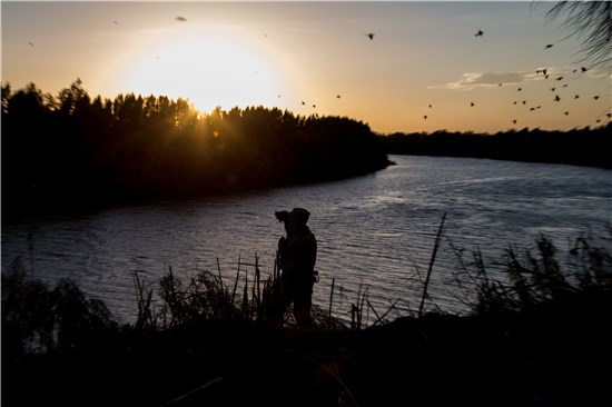 A soldier from the 36th Infantry Division, Texas Army National Guard observes a section of the Rio Grande River at sunset. 