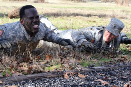 Staff Sgt. Timothy Boutte, the senior mechanic for Company D, 949th Brigade Support Battalion, 56th Infantry Brigade Combat Team, 36th Infantry Division, Texas Army National Guard, pushes through prone rows while Command Sgt. Maj. Michelle Thompson, the battalion's command sergeant major, motivates him to complete the air assault course at Camp Swift, Jan. 8. The course was one of eight events that were part of the 56th Infantry Brigade Combat Team’s Best Warrior Competition. (U.S. Army National Guard photo by Sgt. Michael Vanpool/Released)