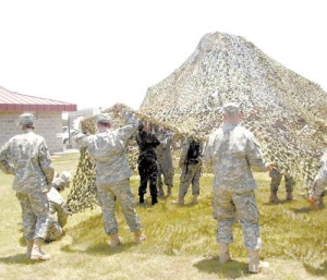Guard members rehearse setting up a “shade structure.” The camo netting significantly cools an area even in the hottest sun allowing guard members to set up a command post or temporary office in even the most barren terrains.