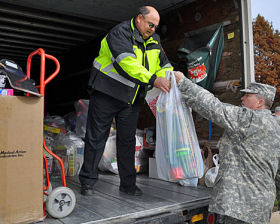 Officer Mark Calvert, left, takes a bag of toys from Corporal Wells of the Texas State Guard, Wednesday at police headquarters. Members of the Guard donated 300 toys to Santa Cop.