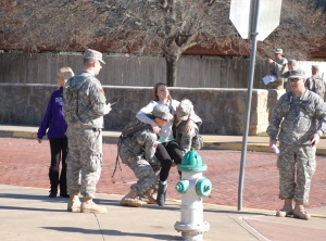 19th Regiment 1st Battalion troops, (L) PFC Joshua Smith and (R) PFC Hunter Becker, carry one of the Texan Star dance team members, Nichole Fort, playing as the injured victim, for medical attention during the WADA exercise while Callie Childers, Texan Star, PFC John Rizo (L) and PFC Ronny Bannister(R) look on.