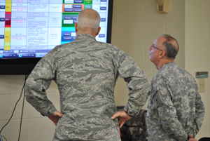 Texas State Guard officers 1st Lt. Carl Mathews, 447th Support Group, 5th Air Wing, and Capt. Joseph Conte, 8th Regiment,   review the emergency operations command information board at the 8th Regiment tactical operations command center