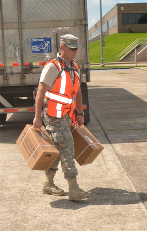 Pfc. Justin Stanton, 8th Regiment, Texas State Guard, carries cases of ready-to-eat meals for residents of Brazoria County