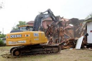 Master Sgt. Ken Walker A heavy 45,000 pound Deere excavator tears down a house in Laredo, Texas, April 9, 2015. The house, identified by local law enforcement as being used for illicit drug activity was recently set ablaze and burned. Texas Joint Counterdrug Task Force's Operation Crackdown destroys drug havens in partnership with city officials and law enforcement agencies. The Texas Joint Counterdrug Task Force partnered with The City of Laredo, the Laredo Police Department and the U.S. Customs and Border Protection to clean up the city and rid the community of crime associated with a drug nexus. (U.S. Army National Guard photo by Master Sgt. Ken Walker/ Released)