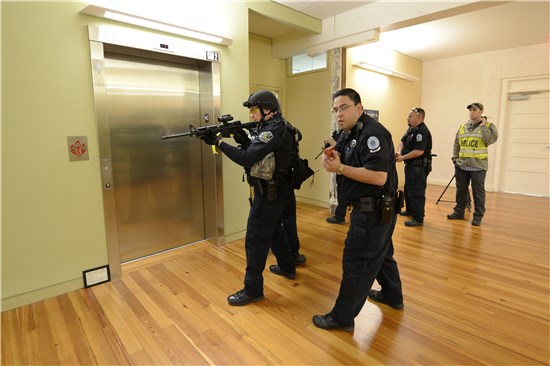 Camp Mabry security officer Gilbert Gonzalez, and members of the Austin Police Department's Counter Assualt Strike Team (CAST), secure work spaces during an active shooter training scenario at Camp Mabry in Austin, Texas, March 19, 2014.