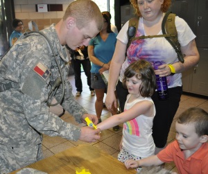 PFC Hunter Becker, assigned to 19th Regiment, 1st Battalion, attaches a Texas Emergency Tracking Network (TETN) band to one of the victims, acting as a role player, as her mother looks on  during a hurricane shelter management exercise, June 7, 2014